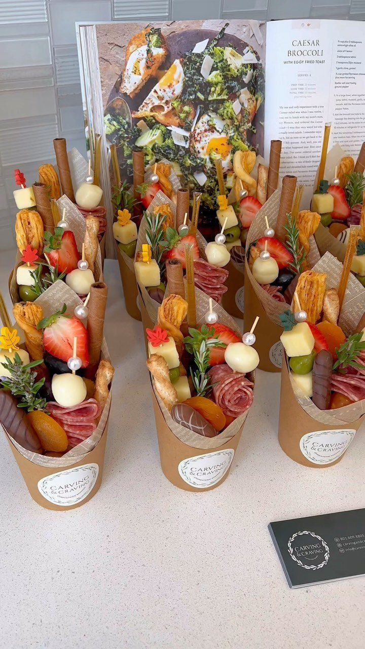 Charcuterie cones filled with meats, cheeses, and fruits arranged on a white counter.