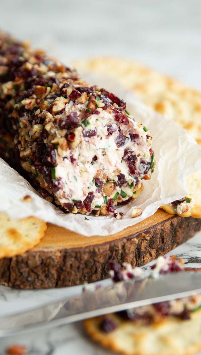 Cranberry and nut coated cheese log on a rustic wooden serving board.