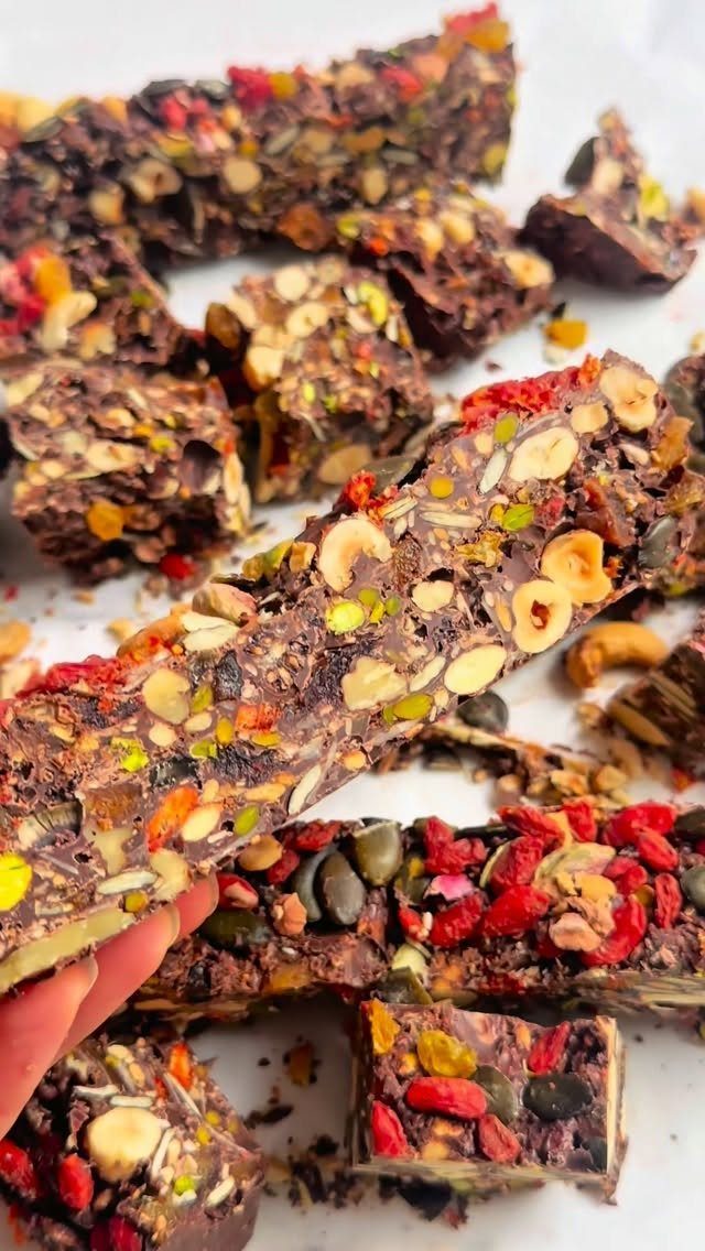 Dark chocolate bark pieces filled with nuts, seeds, and dried red berries.
