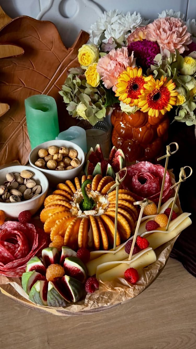Autumn charcuterie board with pumpkin-shaped crackers, salami roses, cheese, and fresh berries.