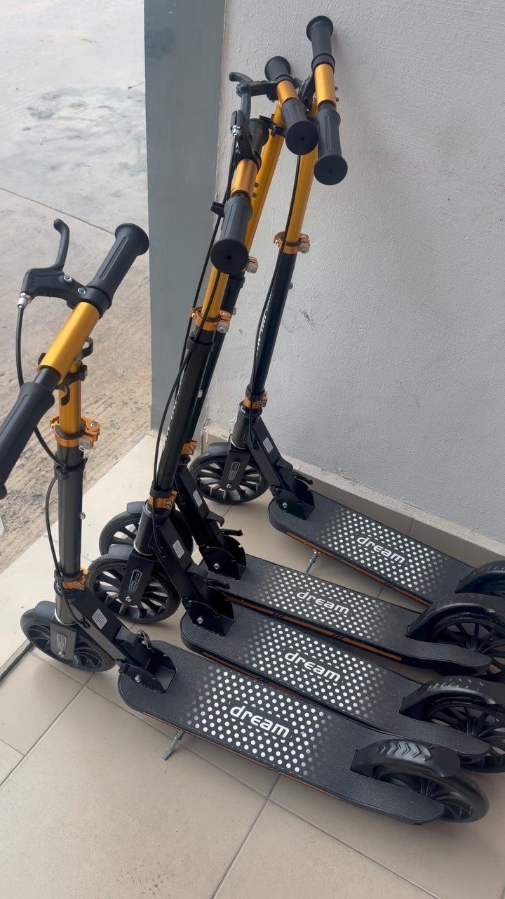 Four black and gold electric scooters lined up against a grey wall.