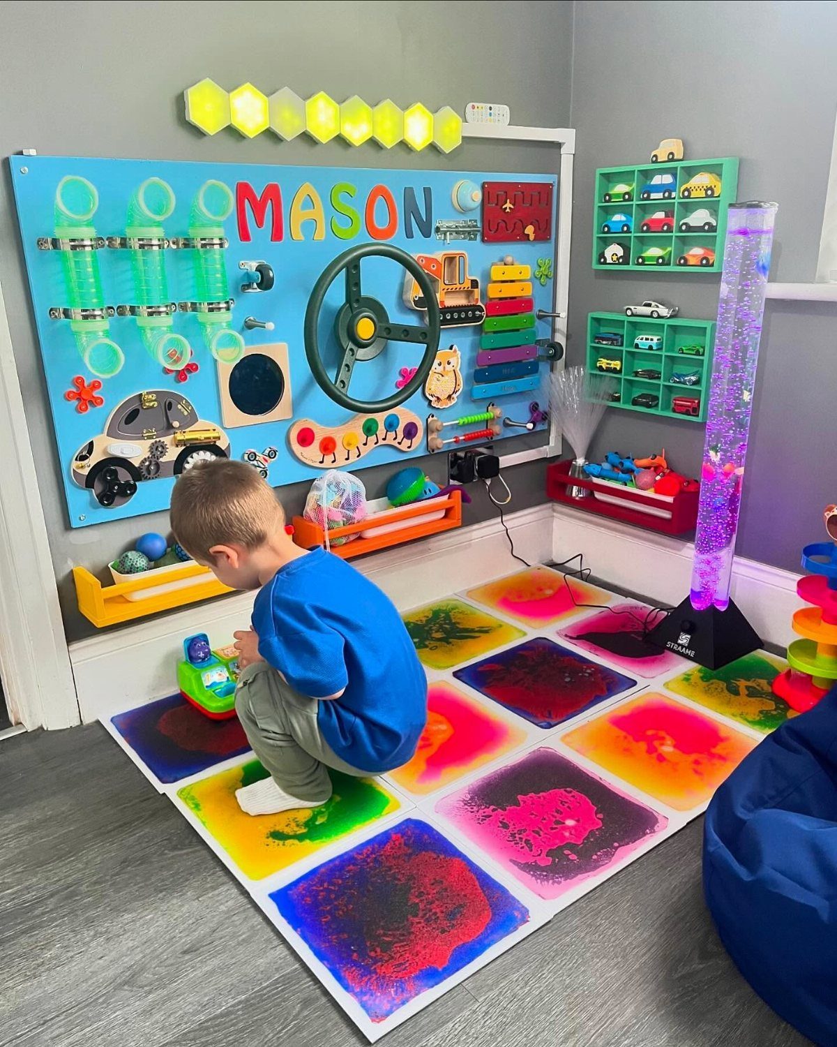 Young boy playing on a colorful illuminated sensory floor mat in a playroom