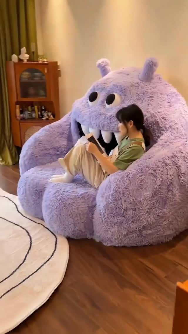 Person reading a book while sitting inside a giant purple monster bean bag chair.