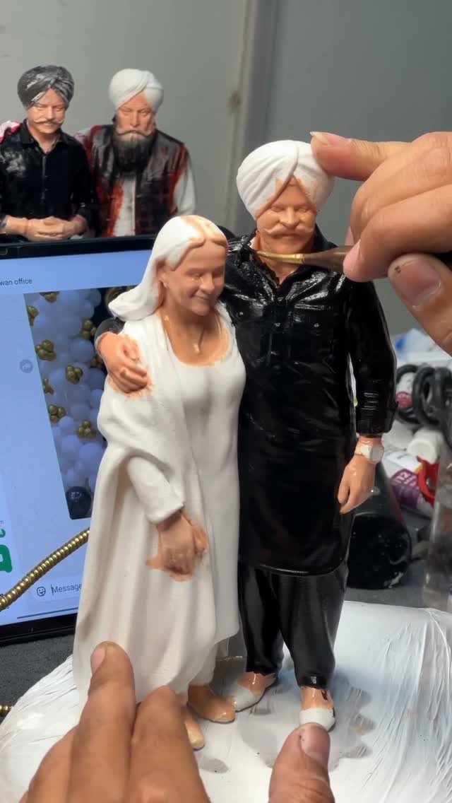 Custom miniature figurines of an elderly couple being hand-painted by an artist.