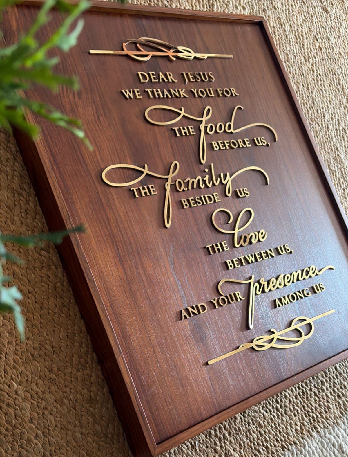 Wooden prayer plaque with gold metallic lettering resting on a tan textured surface