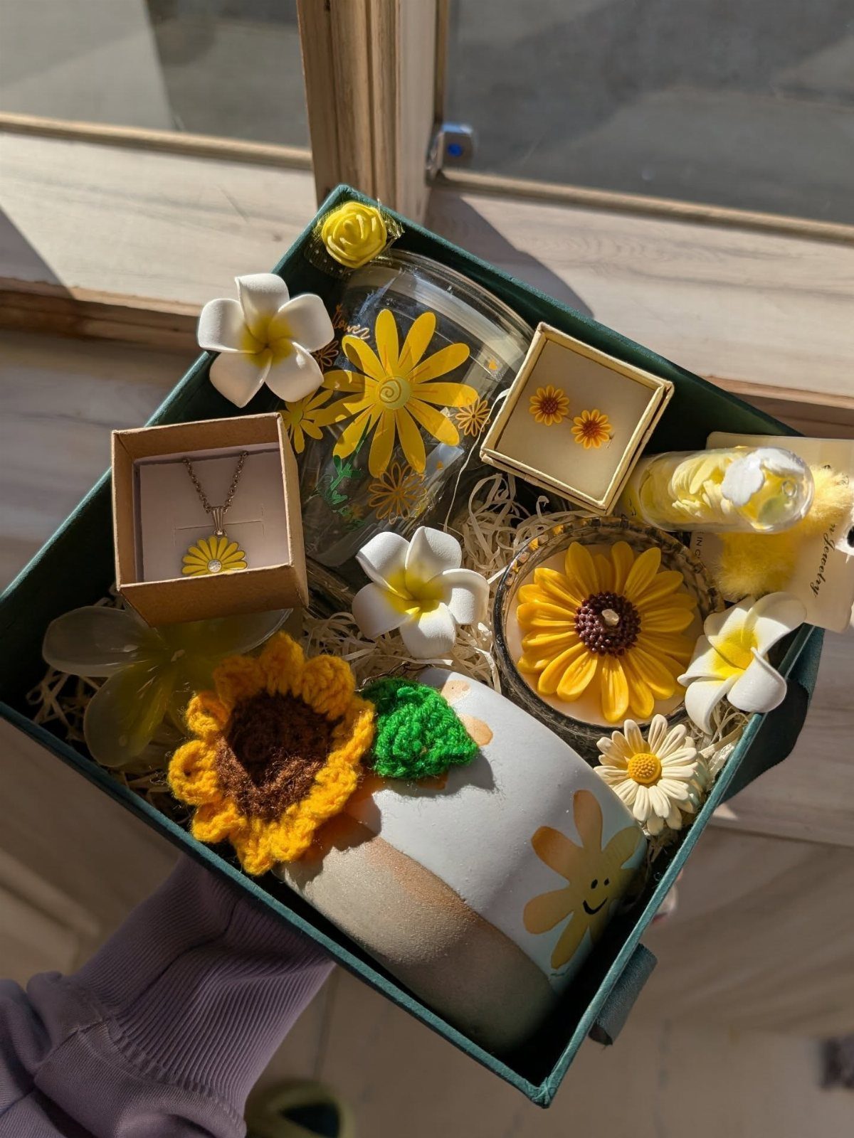 Flower-themed gift box containing a necklace, candle, and mug with yellow sunflowers.