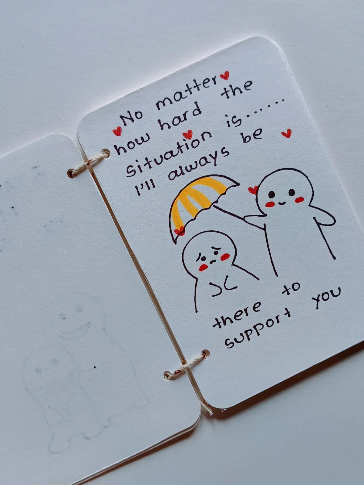 Handmade card with a drawing of two characters under a yellow umbrella and text.