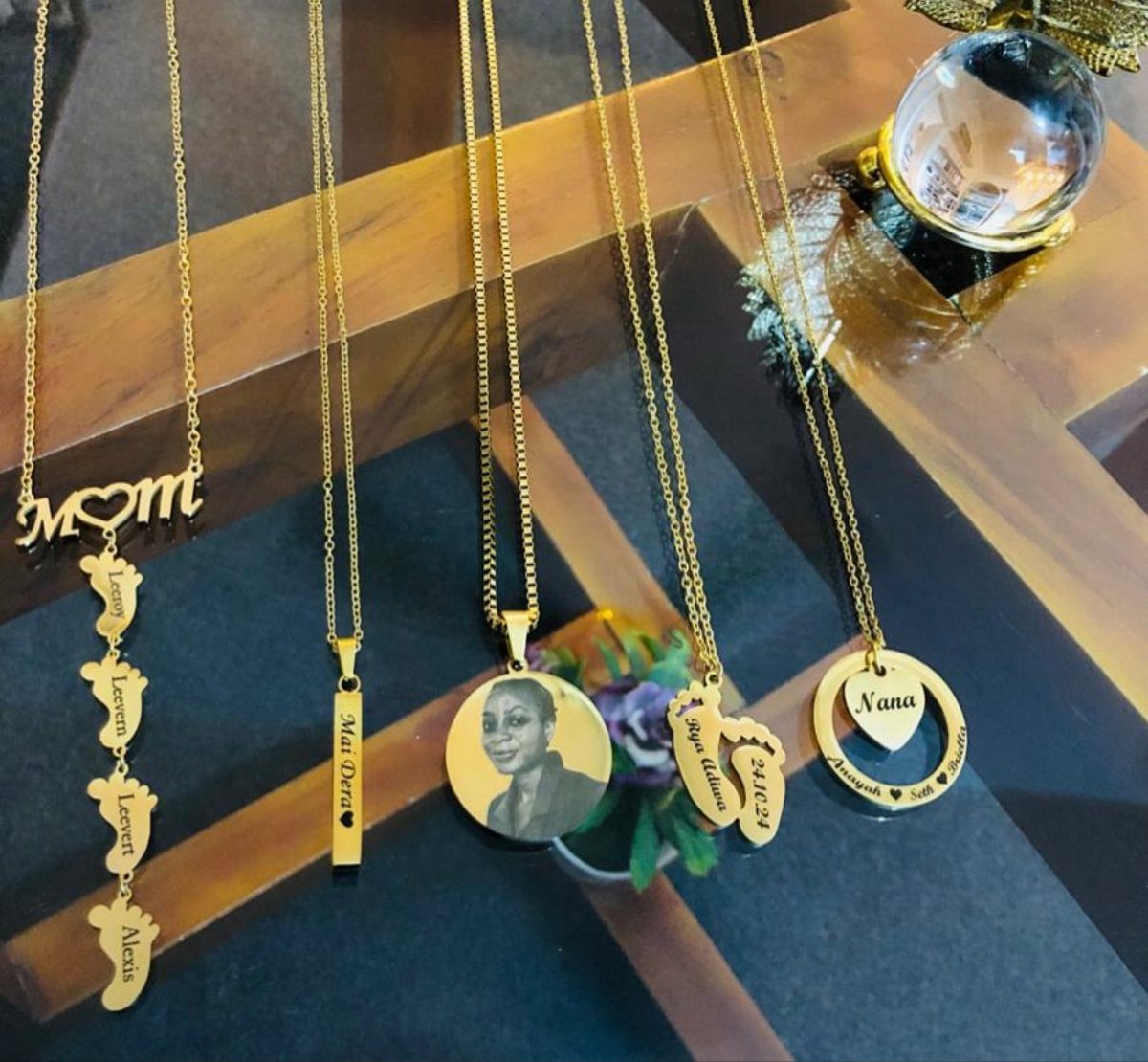Gold personalized necklaces with pendants, including one featuring the word Nana and a heart.