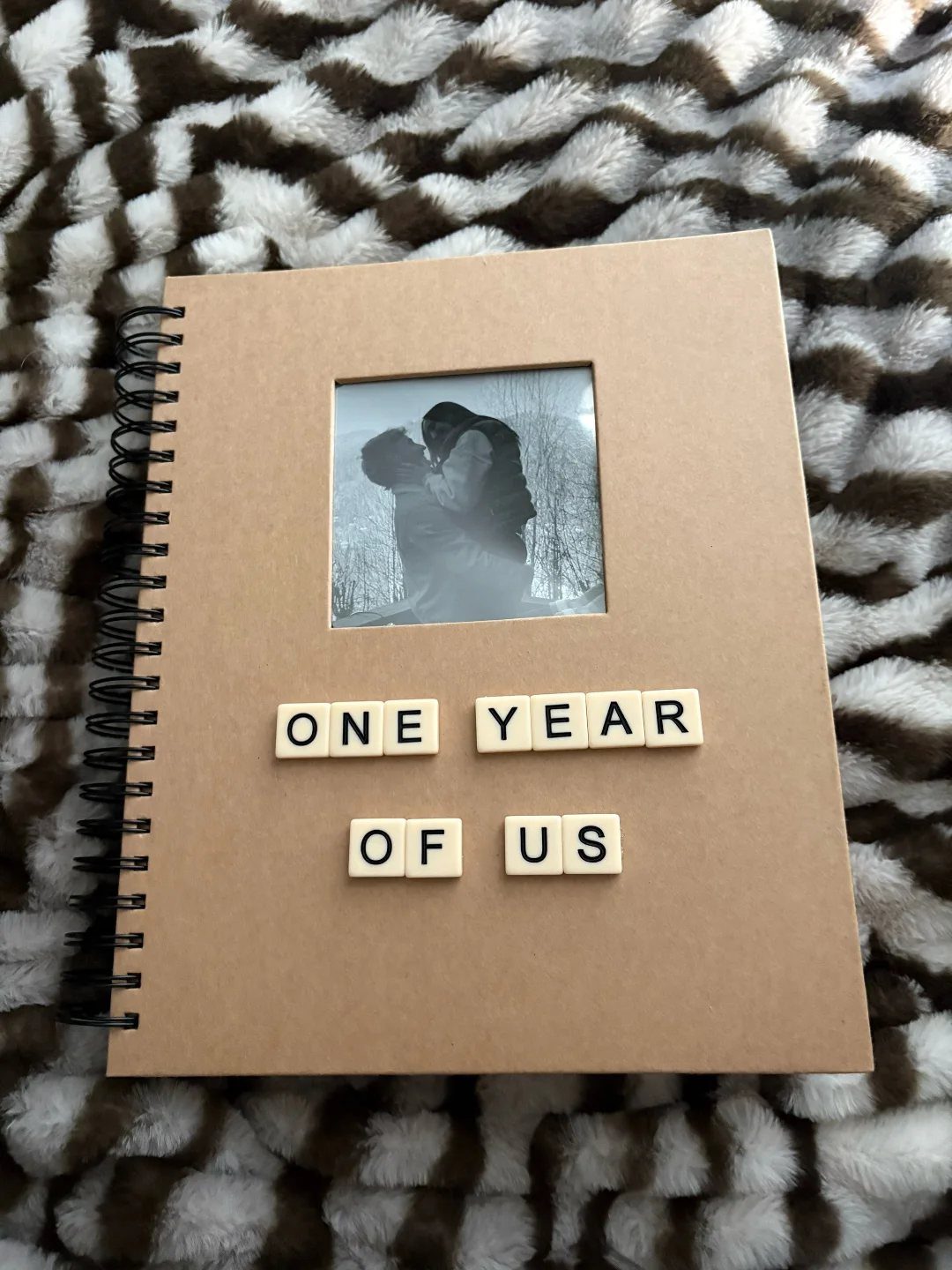 Brown spiral scrapbook with a couple's photo and tiles saying One Year Of Us