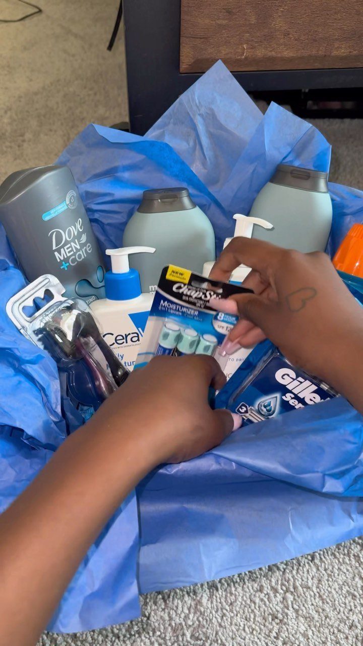 Grooming gift basket with blue tissue paper containing deodorant, lotion, and razors.
