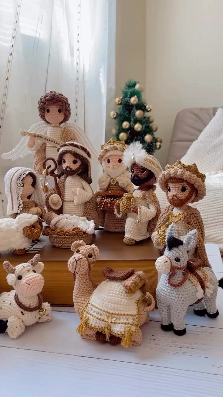 Crocheted nativity scene figures with a small Christmas tree in the background.
