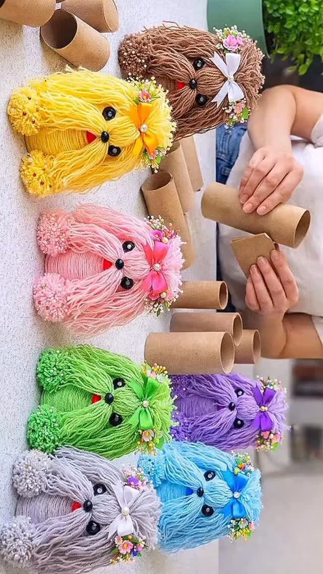 Colorful yarn poodles made from cardboard tubes decorated with bows and flowers.