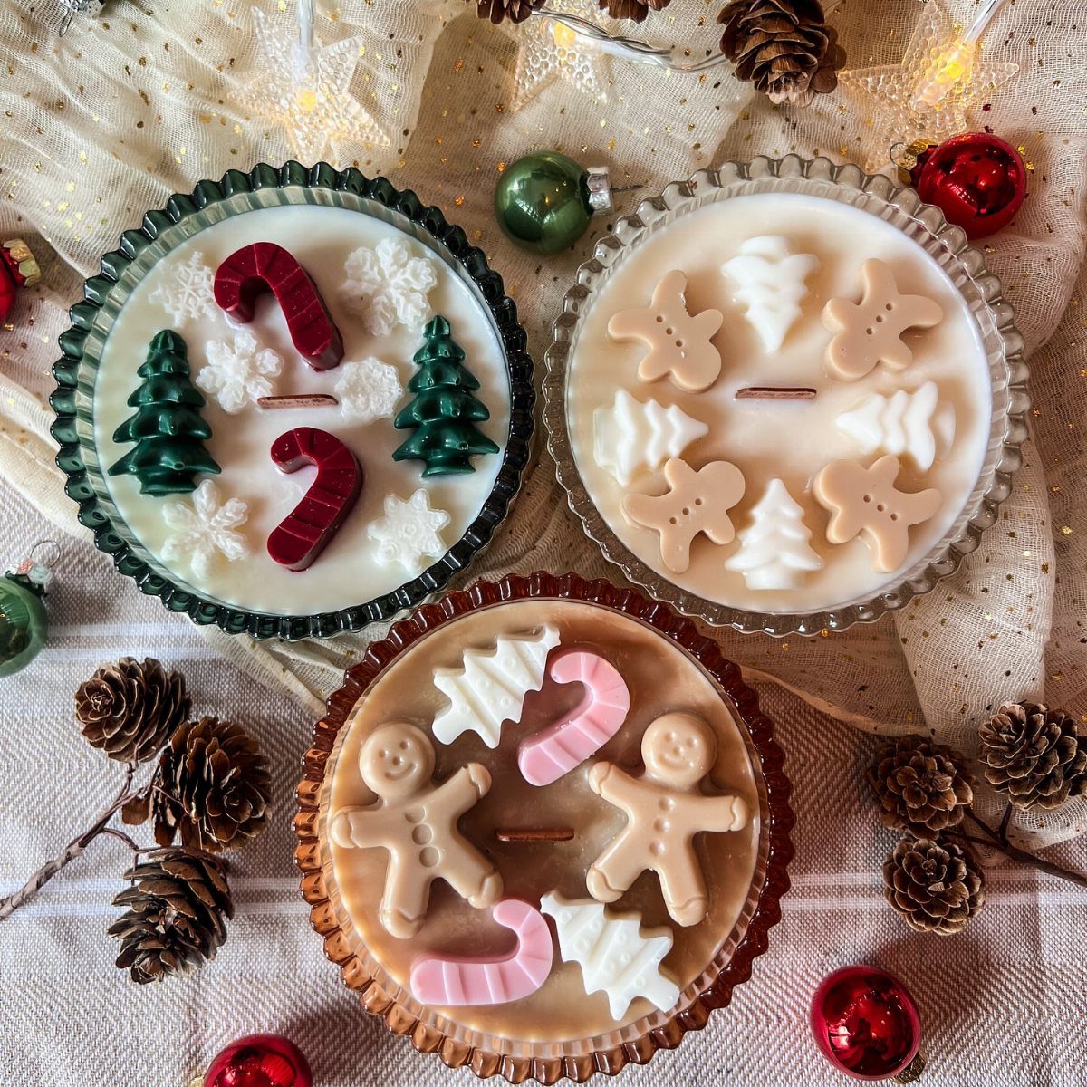 Three festive Christmas candles topped with wax gingerbread men and candy canes.