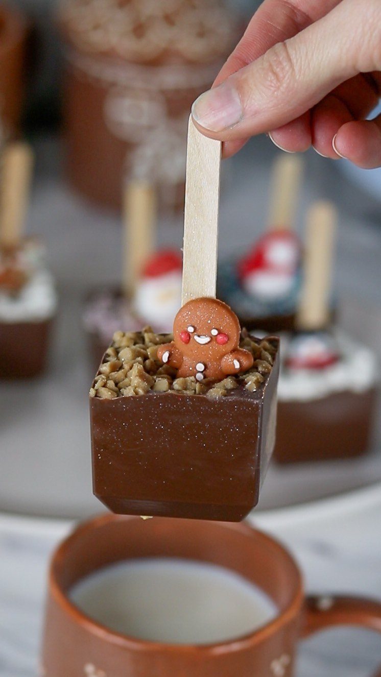 Chocolate cube stirrer with a gingerbread man held over a mug of milk