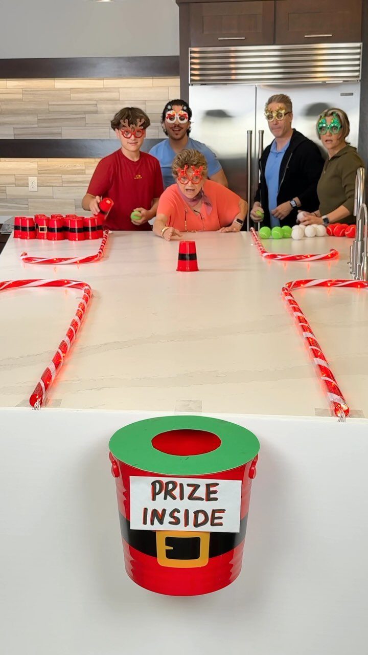 Family playing a homemade carnival game with red cups and a prize bucket.