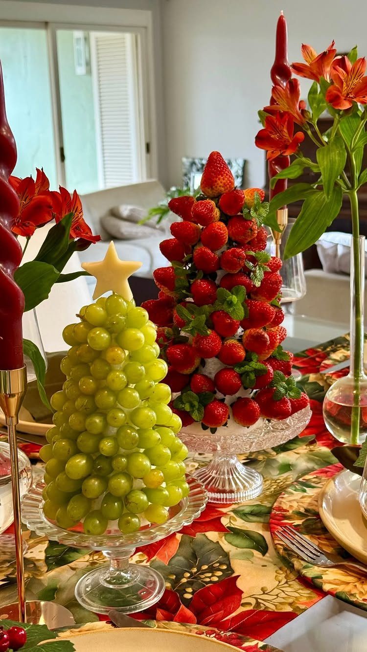 Fruit towers shaped like Christmas trees on a festive holiday dinner table setting.