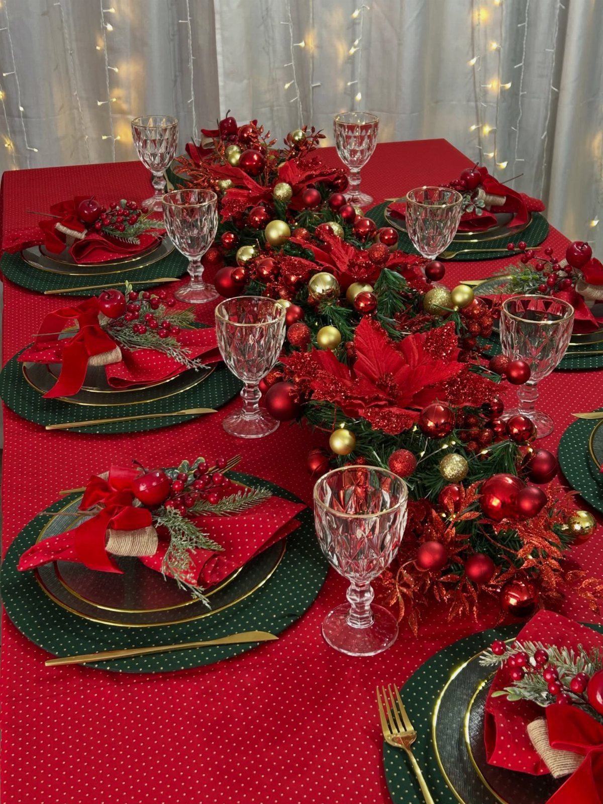 Christmas dinner table setting with red tablecloth, gold plates, and festive floral centerpiece