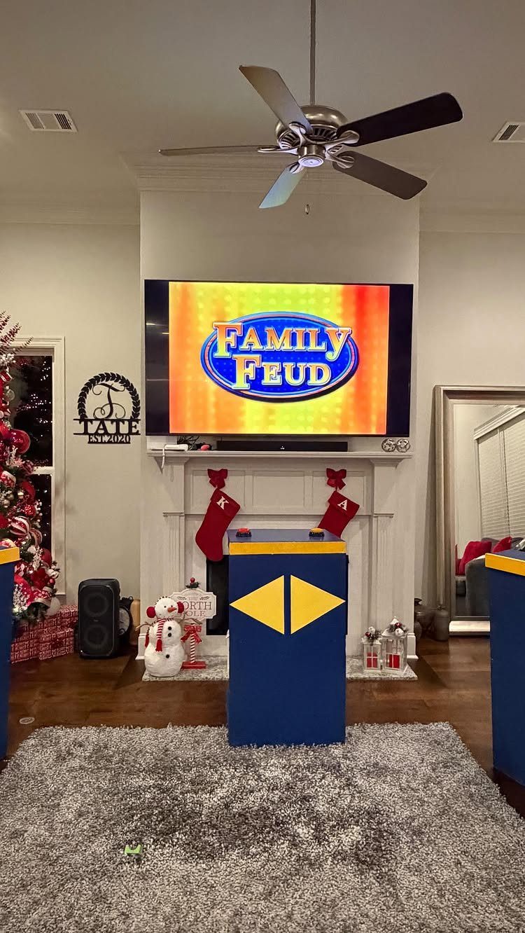 Family Feud game setup in a living room with Christmas decorations and podiums.