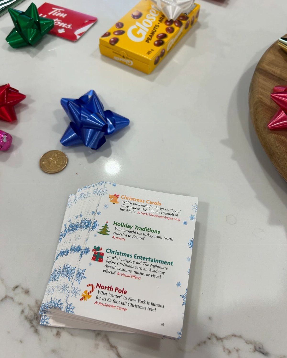 Christmas trivia cards on a marble table with colorful gift bows and chocolates.