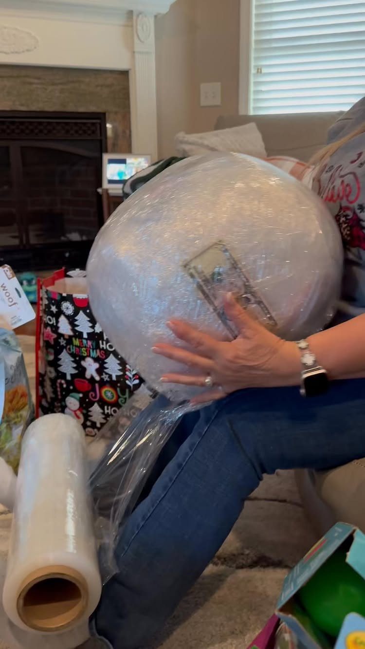 Person holding a large plastic wrap ball with money inside for a game.