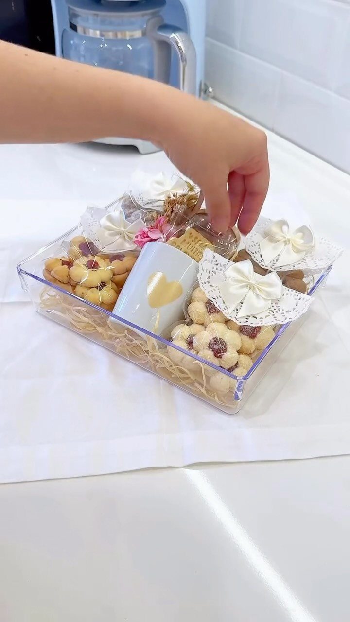 Clear acrylic gift tray with thumbprint cookies, a heart mug, and wrapped treats.