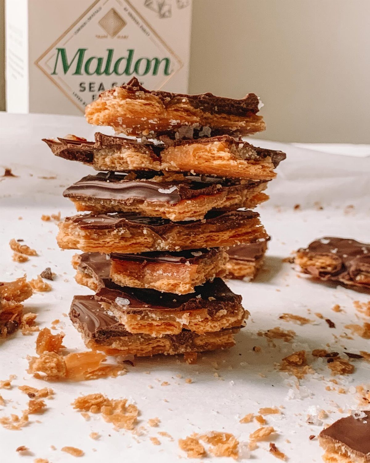 Stacked salted caramel Christmas crackers with chocolate and sea salt on white parchment.