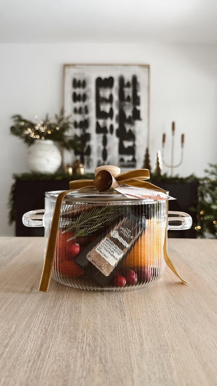 Glass jar filled with orange, cinnamon, and cranberries tied with a gold ribbon.