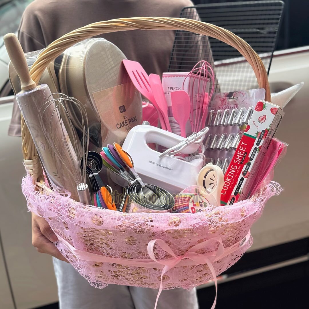 Baking gift basket with pink tools, hand mixer, and cake pans in lace basket