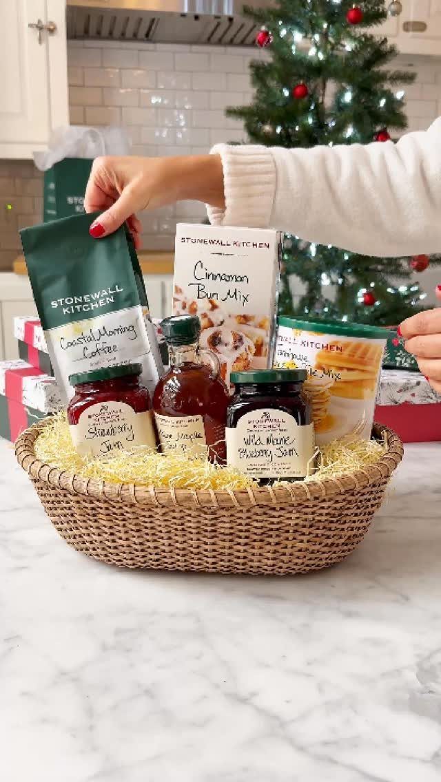Wicker gift basket filled with breakfast items and coffee near a Christmas tree.