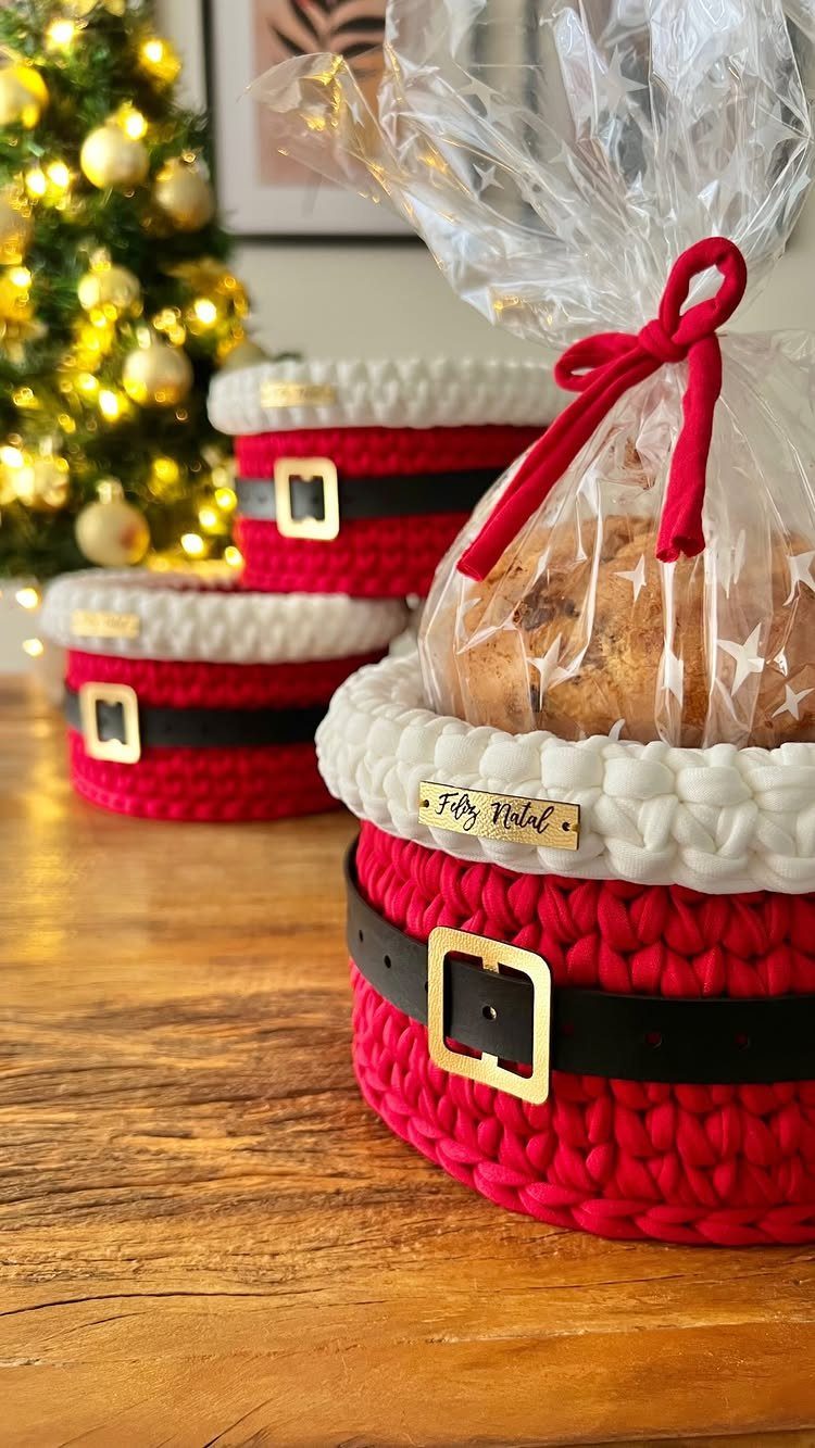 Crocheted Santa suit gift baskets with black belts and gold buckles on wood.