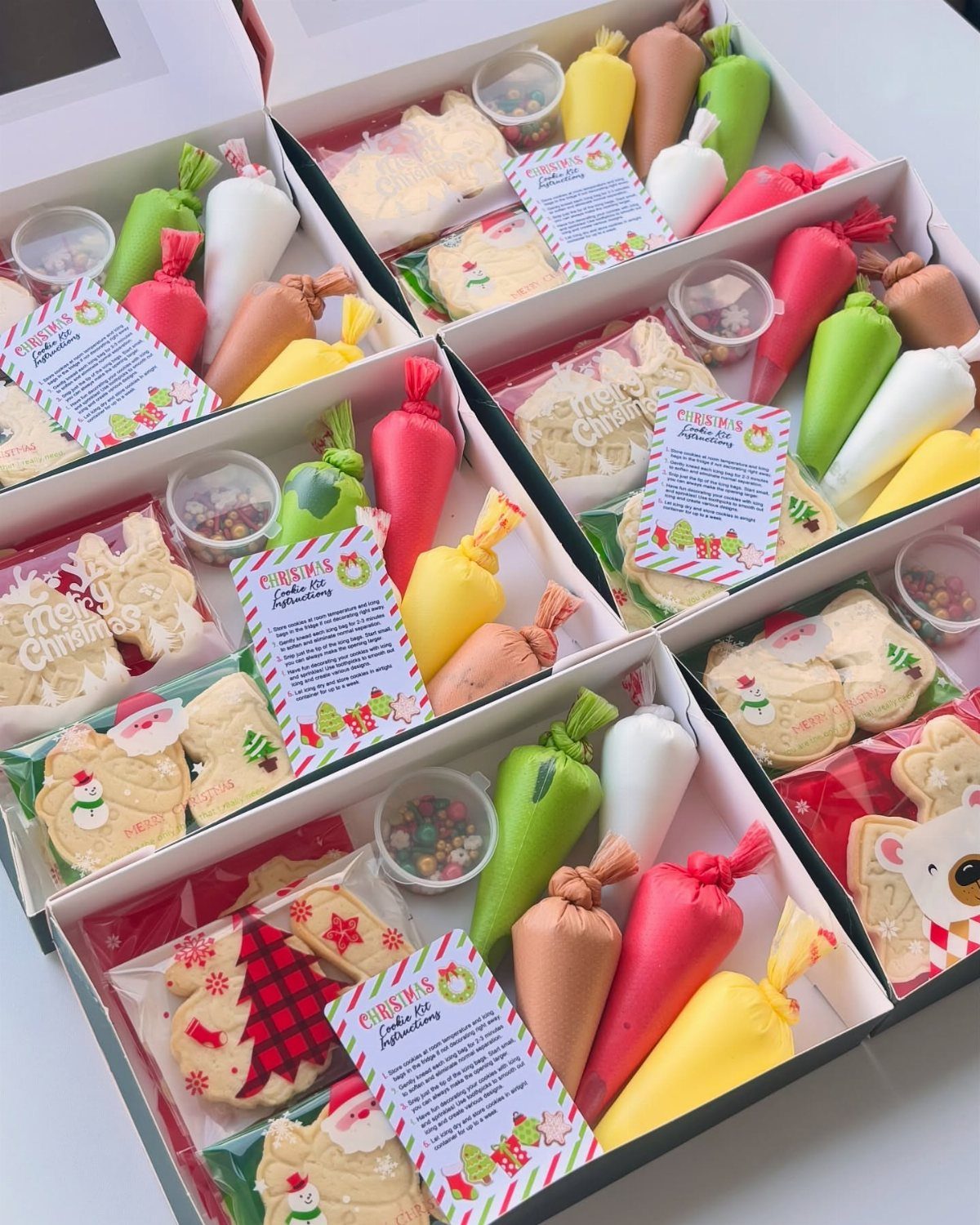 Cookie decorating kits in white boxes with frosting bags and sprinkles.