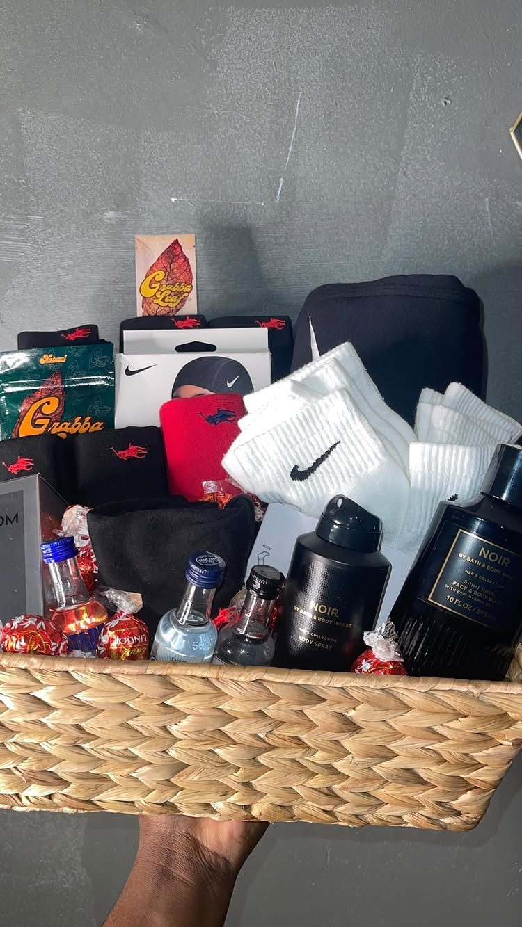 Woven gift basket containing Nike socks, a beanie, liquor bottles, and candies.