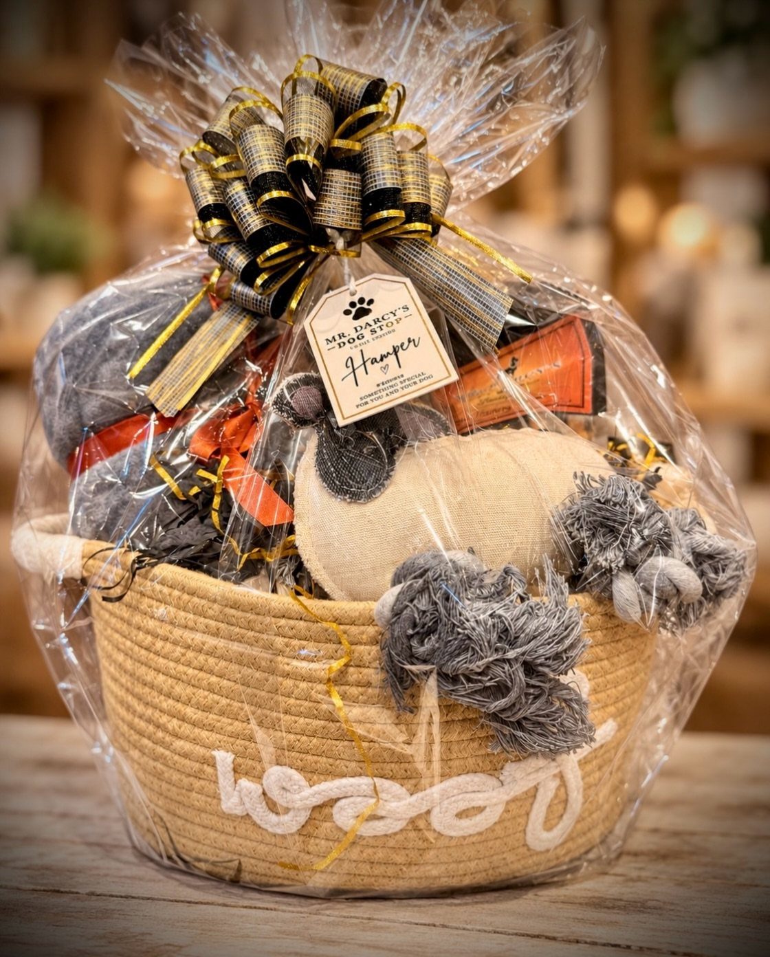 Woven gift basket filled with plush dog toys and treats wrapped in cellophane.