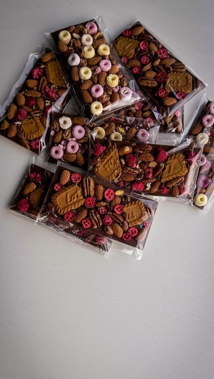 Wrapped chocolate bars topped with nuts and berries on a white background
