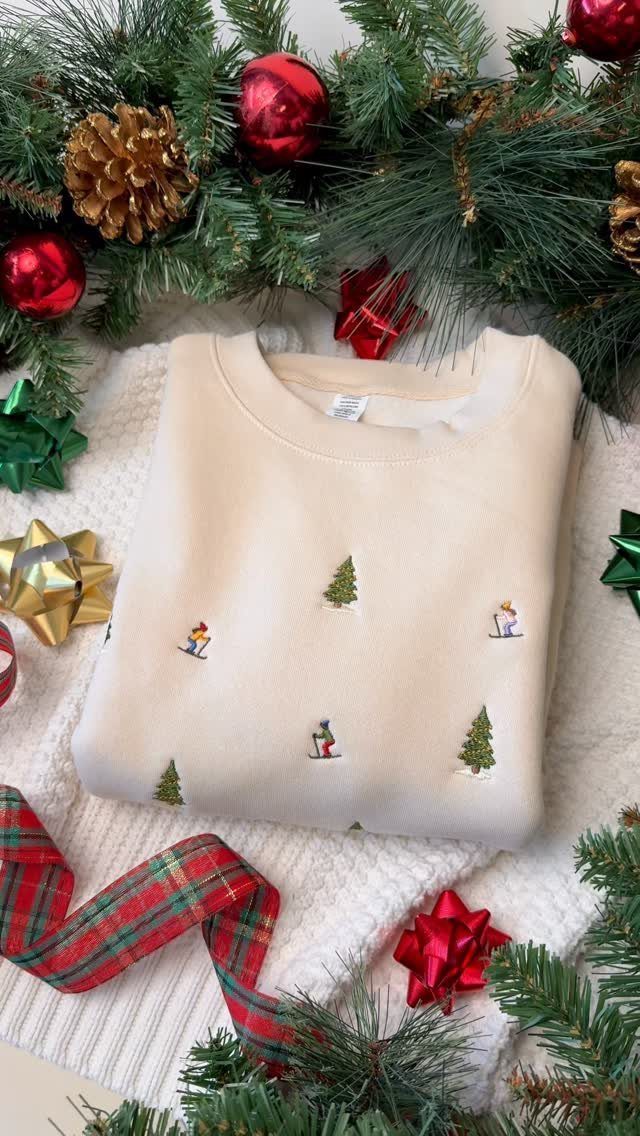Cream sweatshirt with Christmas embroidery surrounded by pine branches and festive ornaments