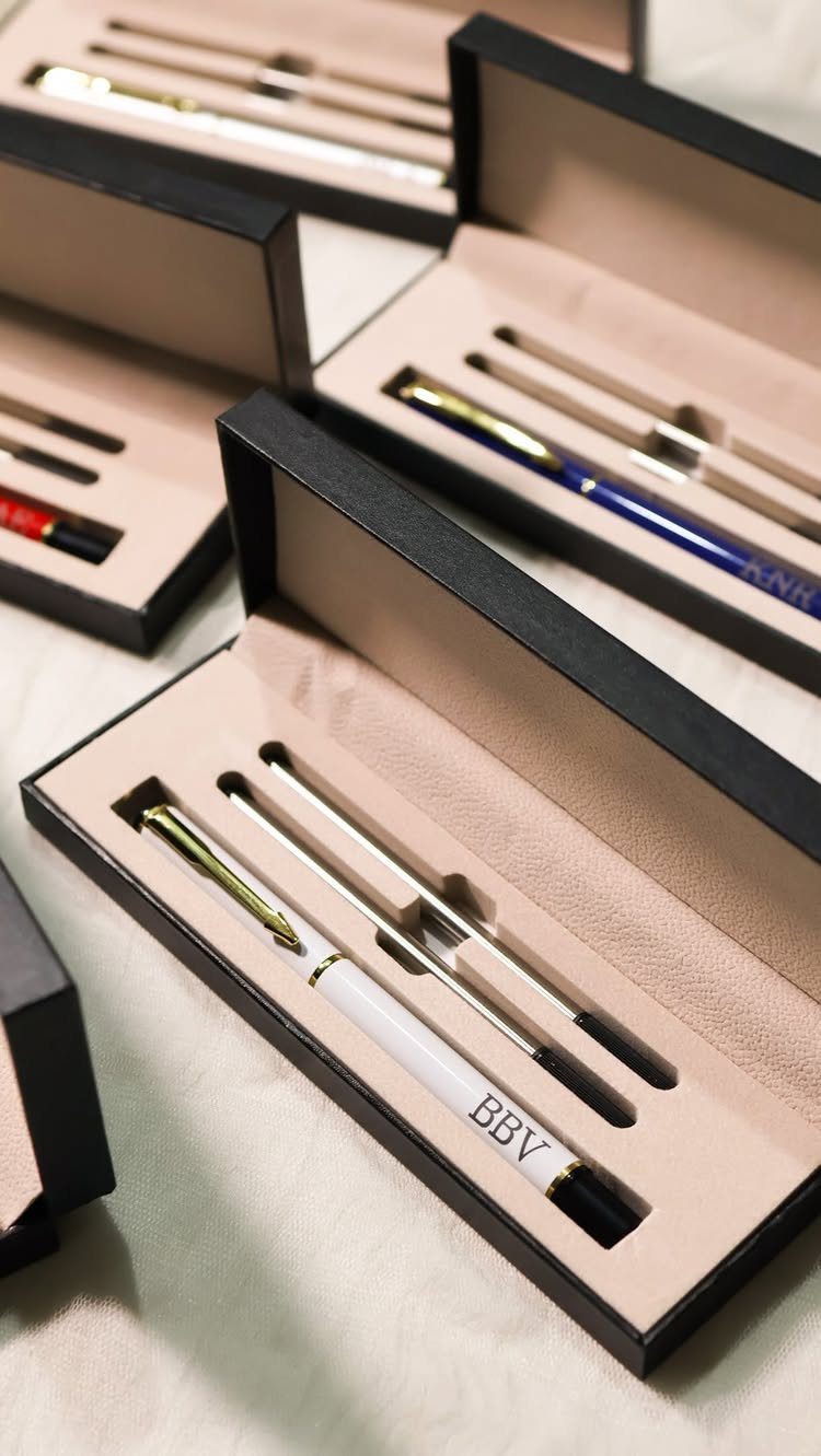 Engraved white and silver pens resting in elegant black gift boxes.