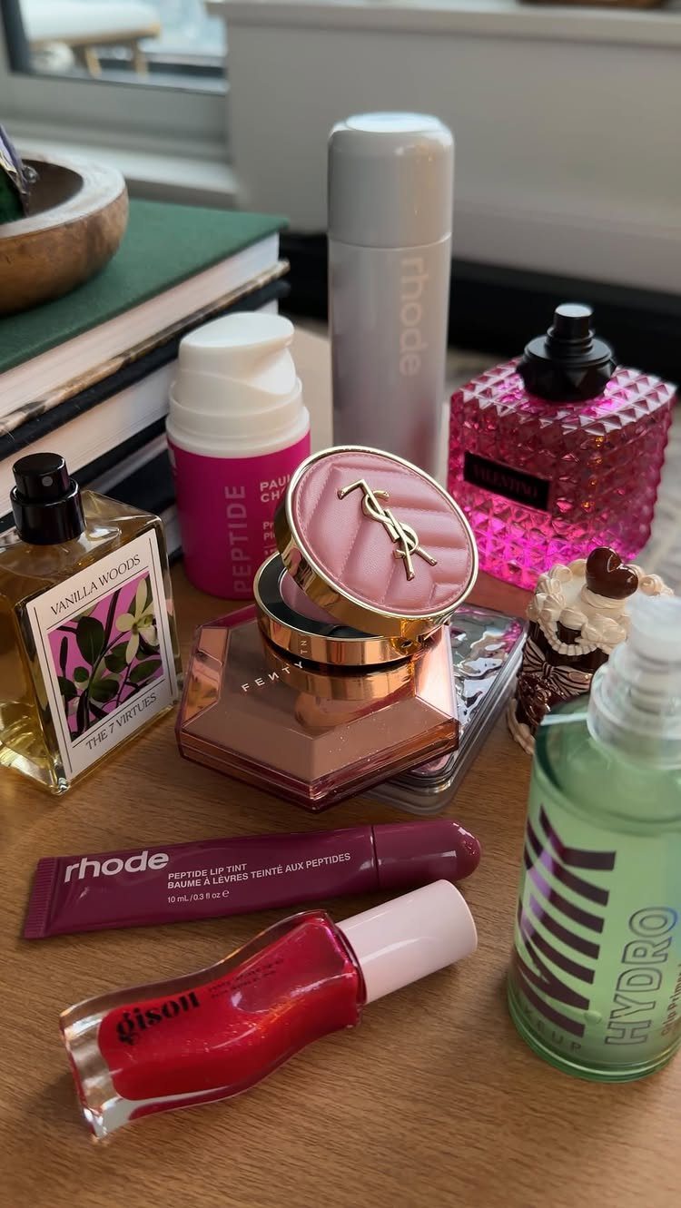 Beauty and skincare products including perfumes and nail polish on a wooden table