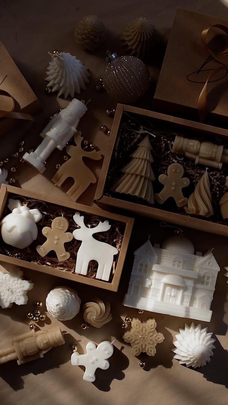 Decorative white and beige candles in festive shapes arranged in gift boxes.