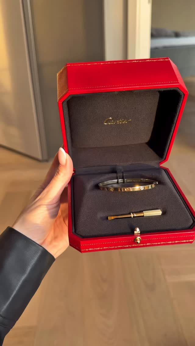 Gold bangle bracelet in a red octagonal jewelry box held by a hand