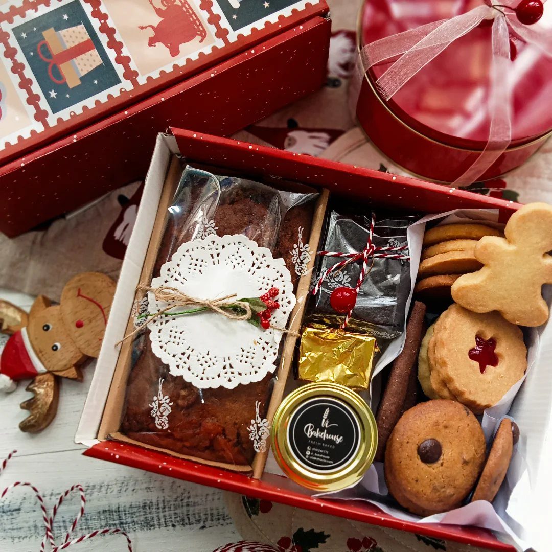 Assorted gourmet treats and cookies in a red holiday gift box.
