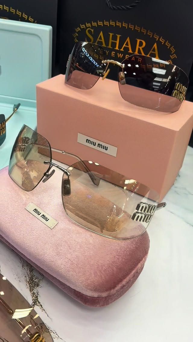Designer sunglasses on pink boxes and a velvet case with a shopping bag.