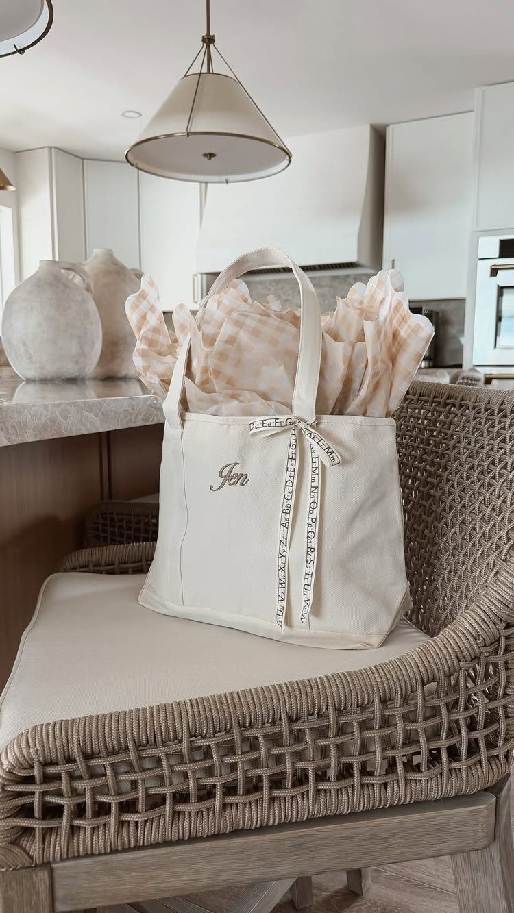 Personalized cream canvas tote bag with embroidery sitting on a woven chair