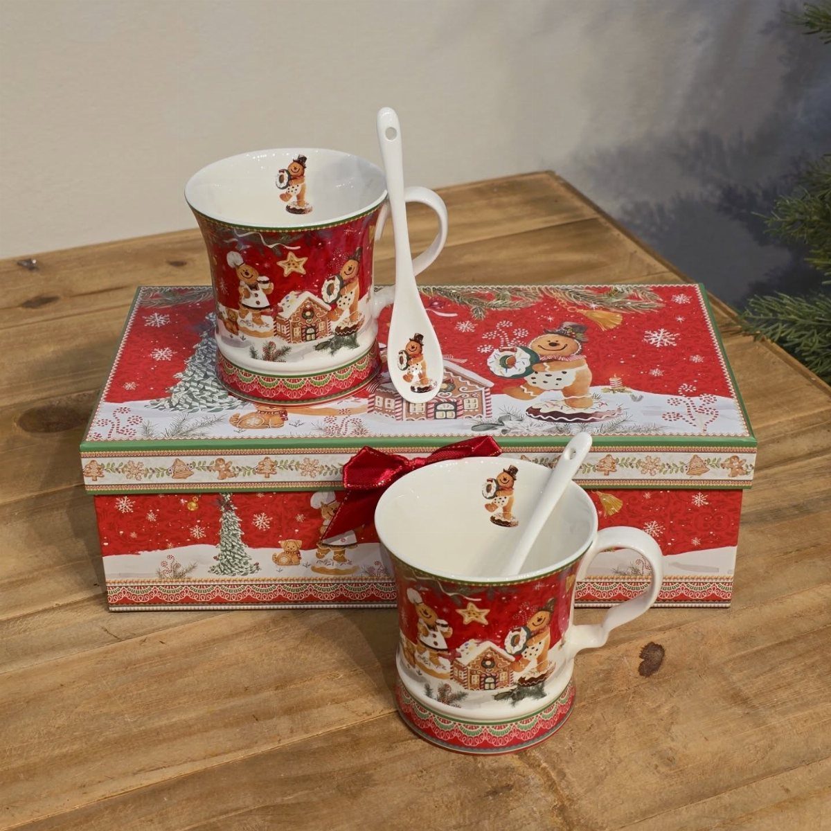 Two festive ceramic mugs featuring gingerbread house illustrations with matching spoons and gift box.