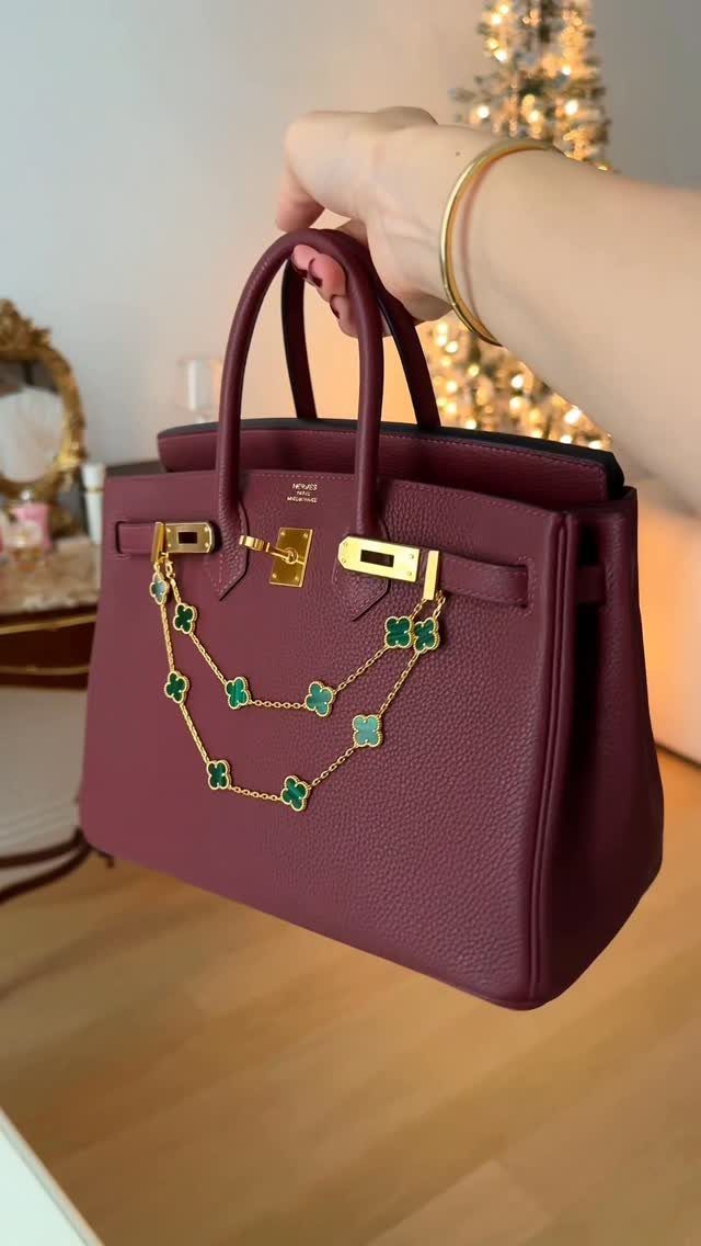 Burgundy leather handbag with gold clover chain held in front of Christmas tree
