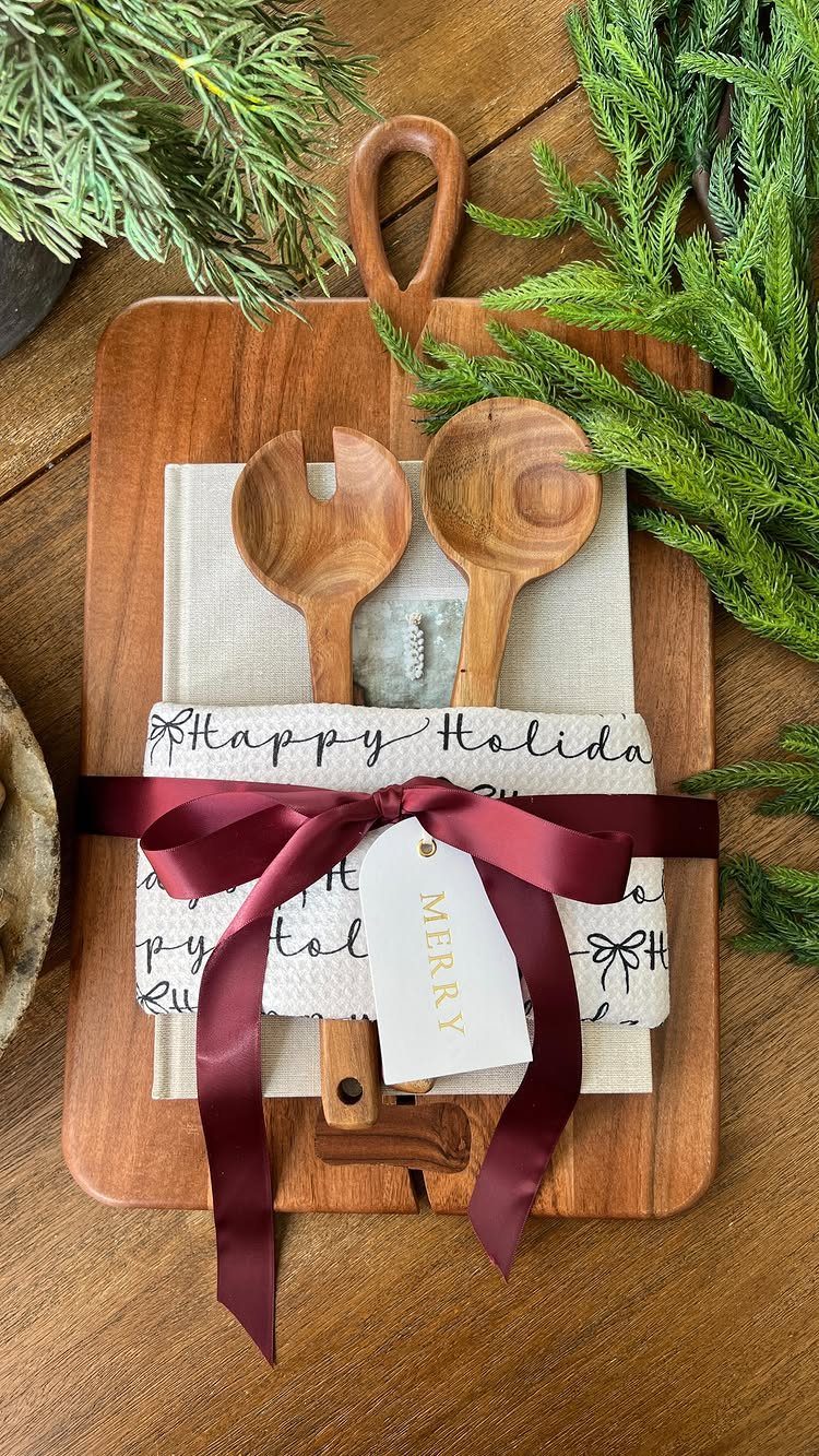 Wooden cutting board gift set with salad servers, holiday napkin, and burgundy ribbon.