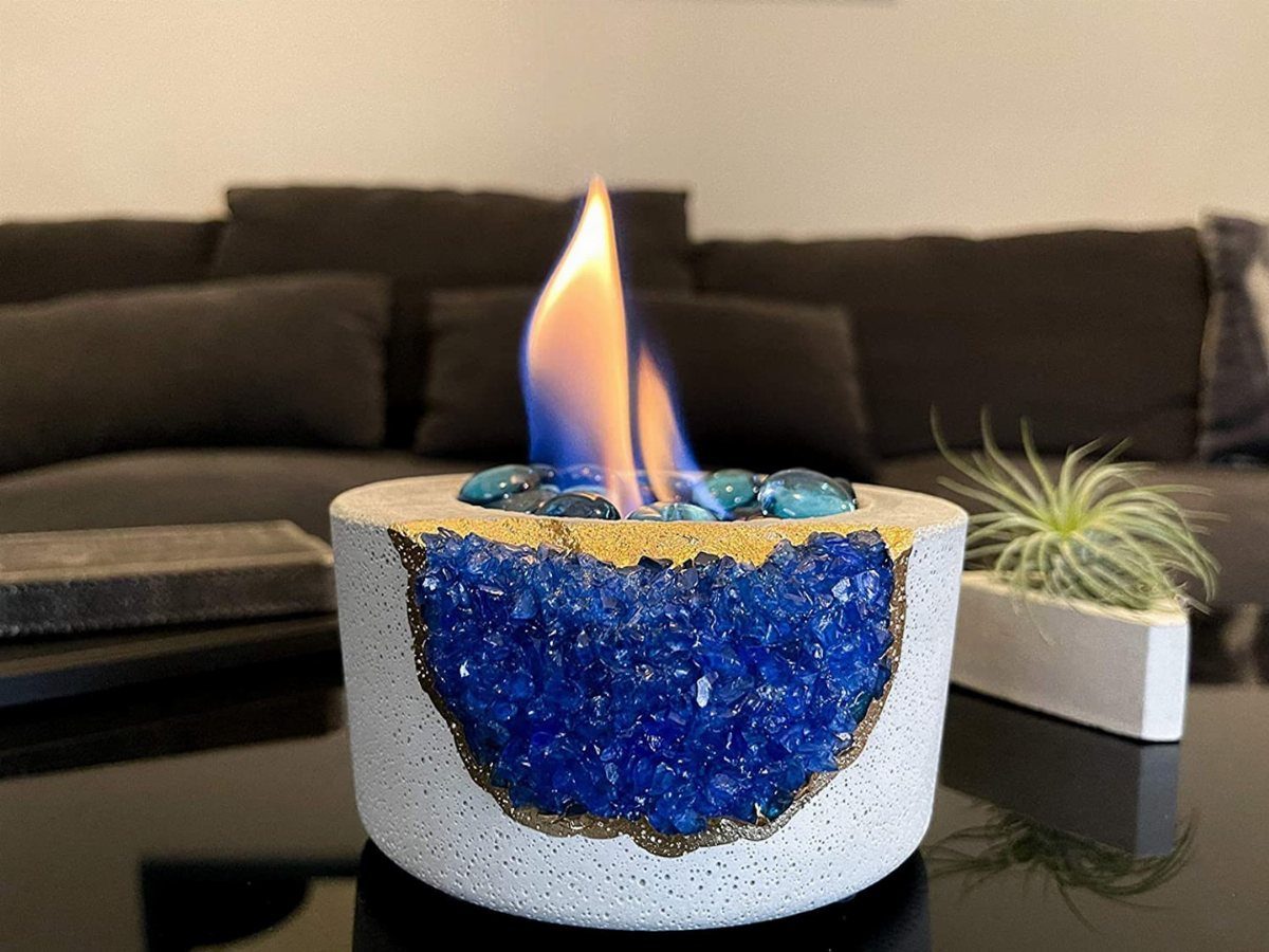 Blue crystal geode candle holder with a bright flame on a dark table