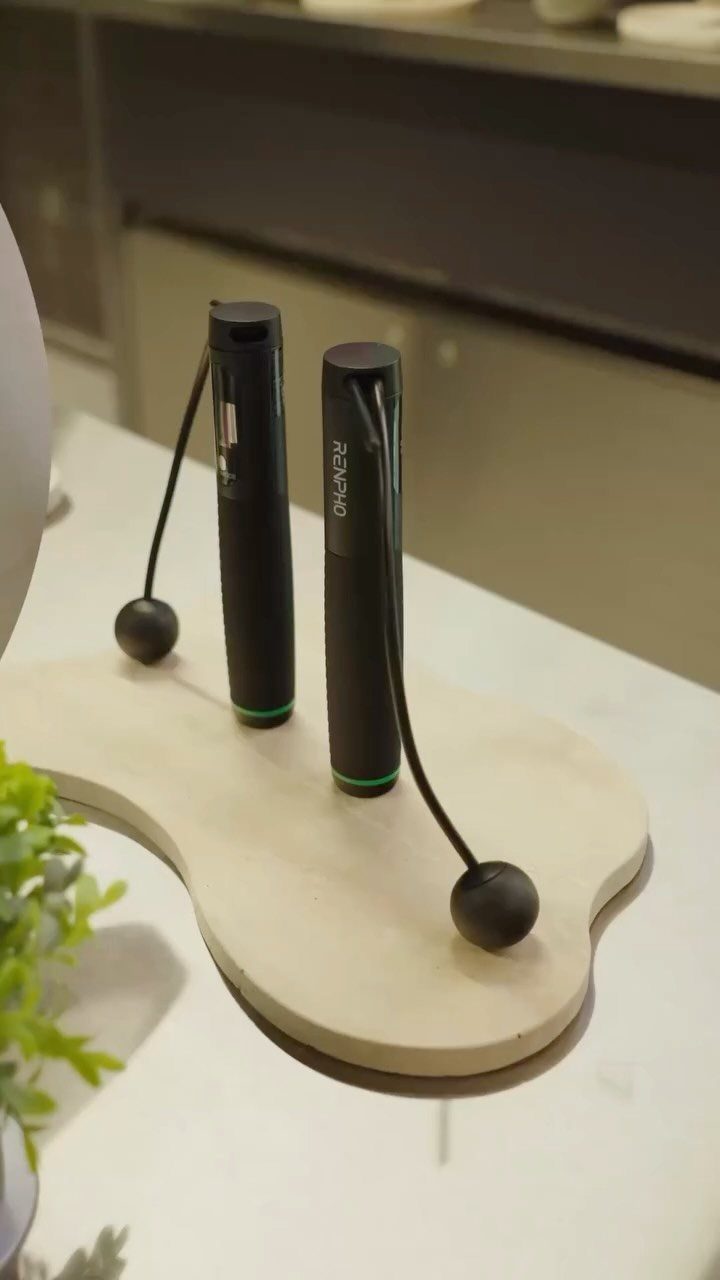 Two black handheld massage devices resting on a light wooden tray.
