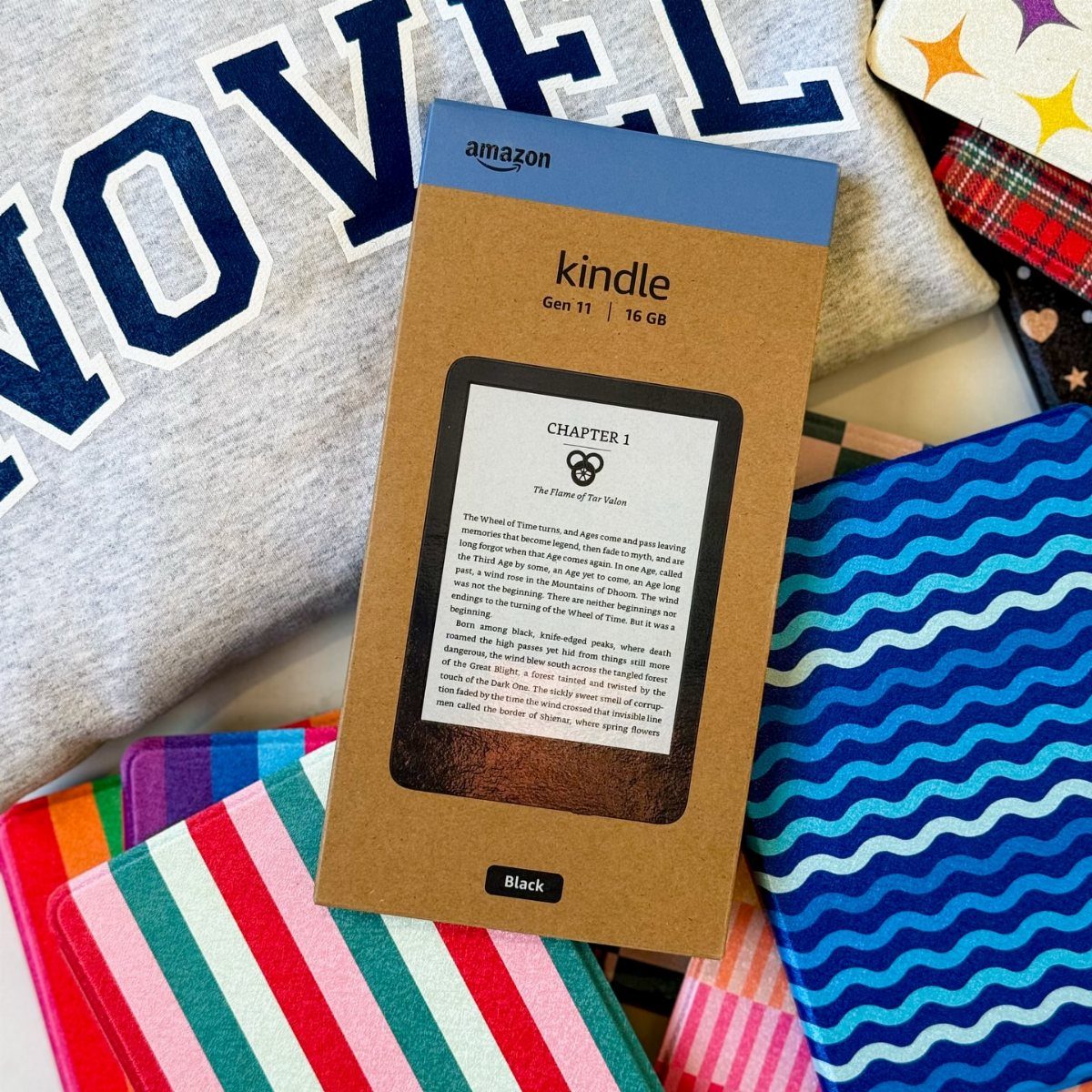 Amazon Kindle box on a grey sweatshirt surrounded by colorful patterned notebooks