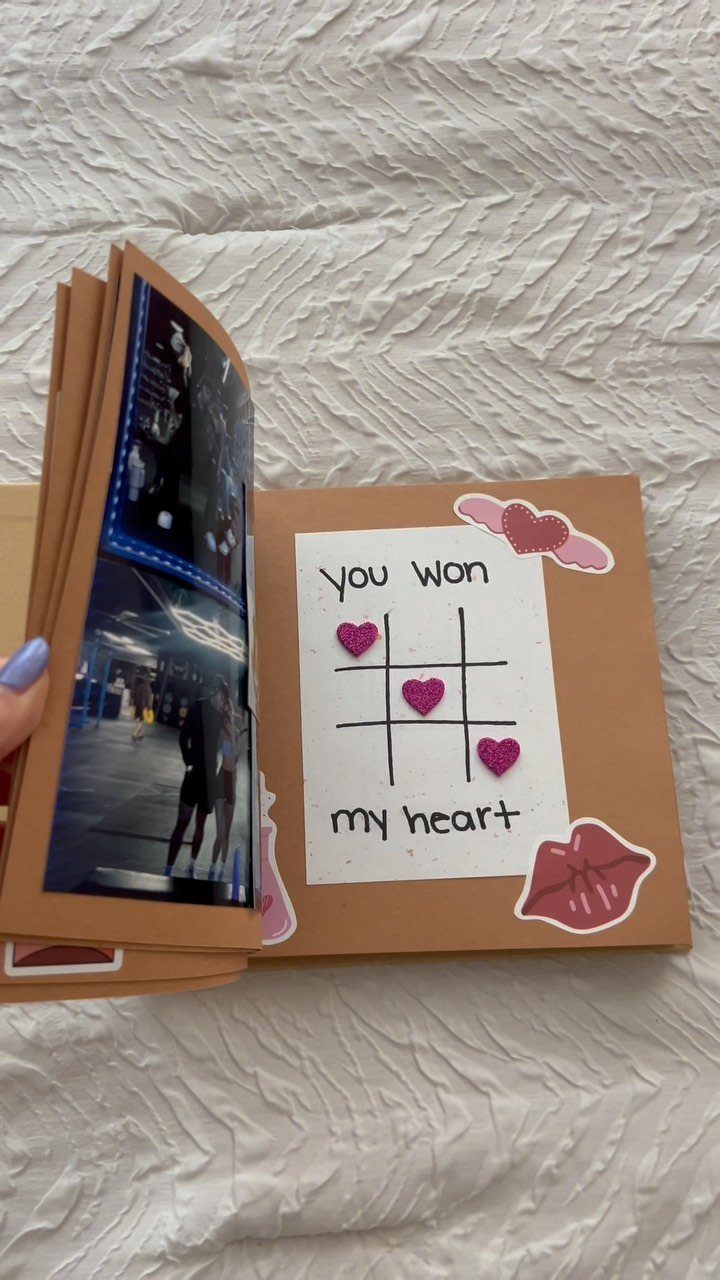Handmade scrapbook with a couple's photo and a heart-themed tic-tac-toe card.