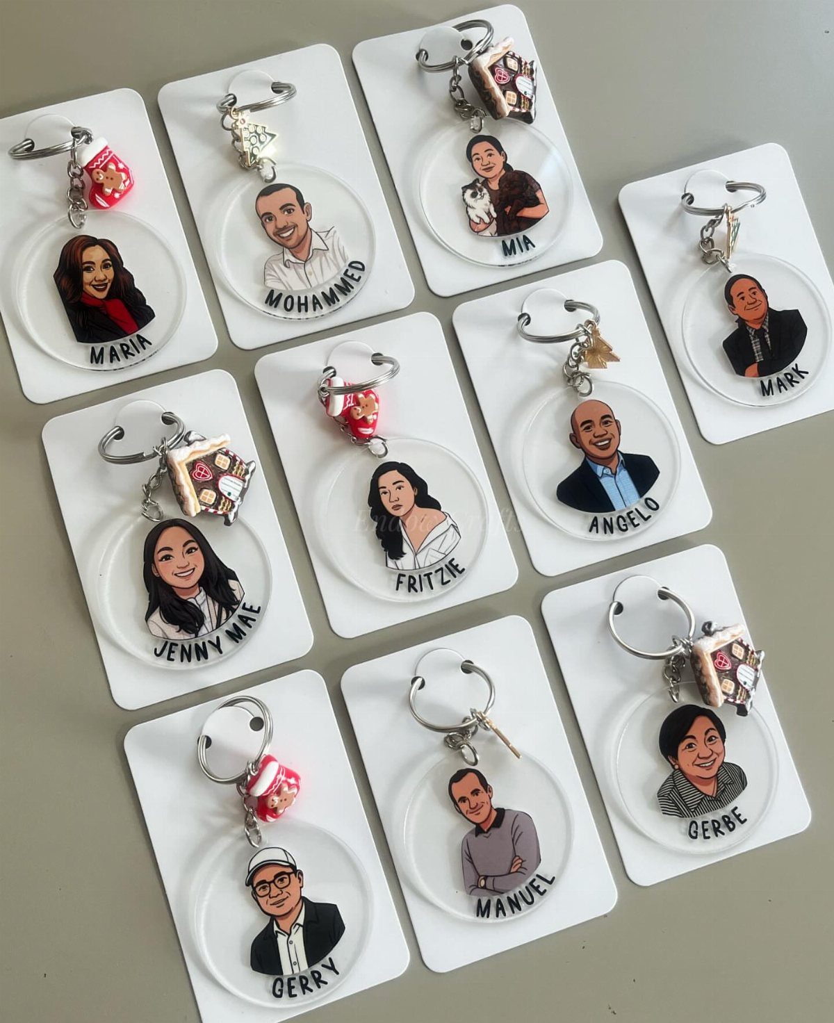 Customized keychains with cartoon portraits and names on white backing cards.